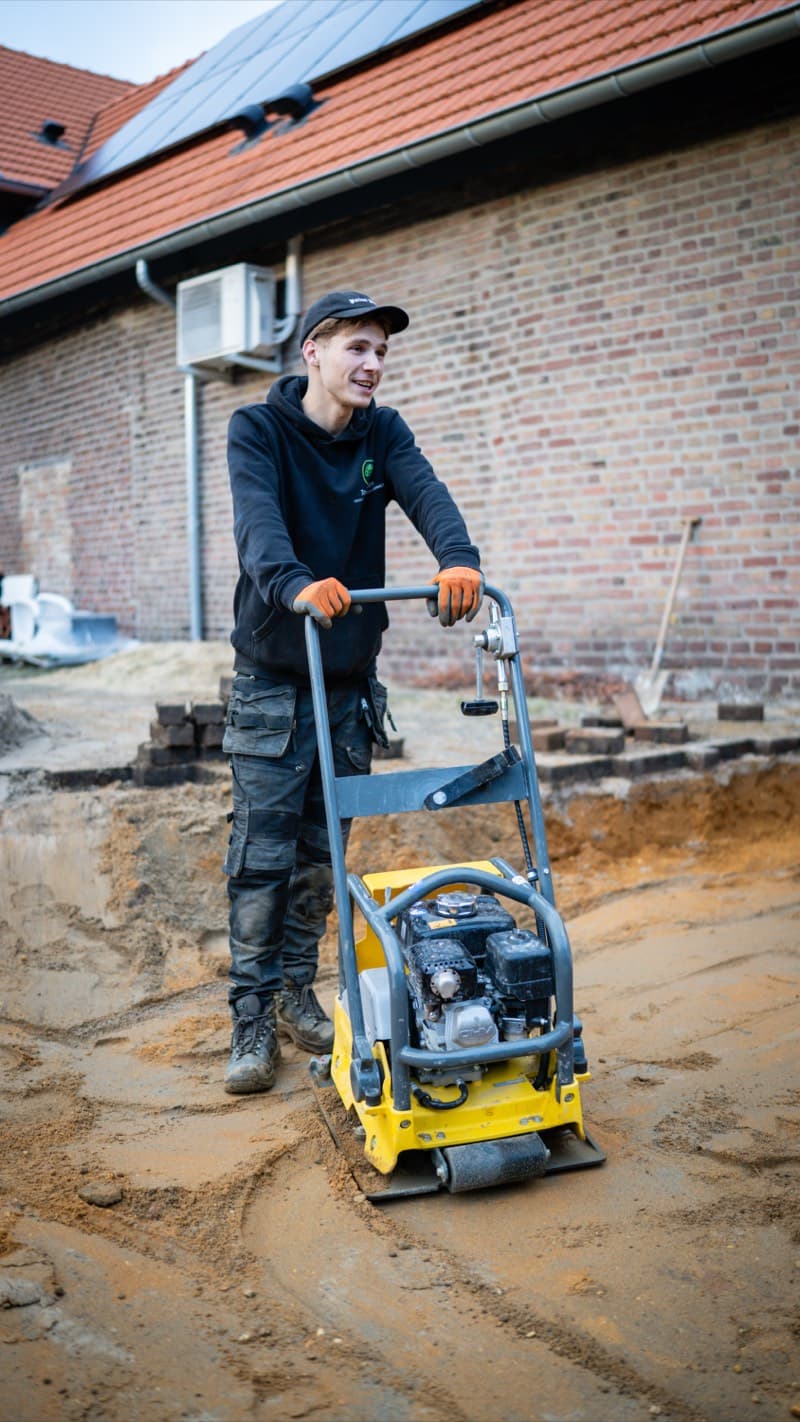 Top Tuinen medewerker aan het werk met trilplaat